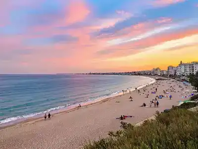 Couples and families enjoying Larnaca's beach at sunset.