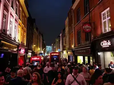 Vibrant London nightlife with crowds and illuminated pubs.