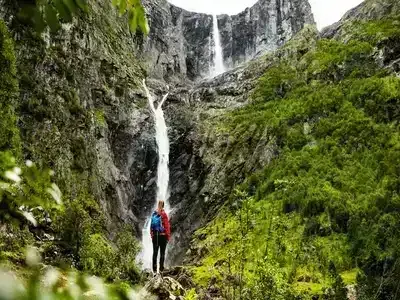 A hiker looking up to the Mardalsfossen waterfall.