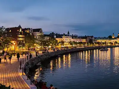 Evening view of Tampere&rsquo;s waterfront with families strolling.