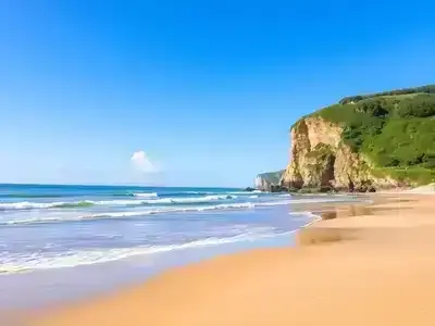 Normandy beach with golden sand and lush green cliffs.
