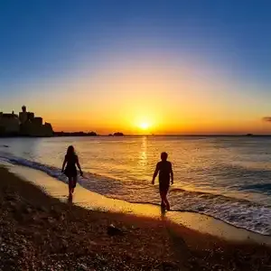 Couples enjoying a sunset walk on Rhodes beach.