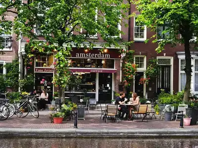 Couples enjoy coffee by Amsterdam&rsquo;s scenic canals.