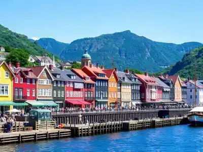 Colorful waterfront houses in Bergen with mountains backdrop.