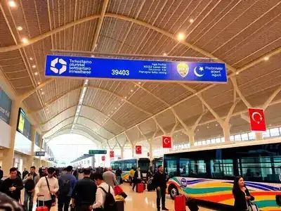 Busy airport terminal in Turkey with travelers and shuttles.